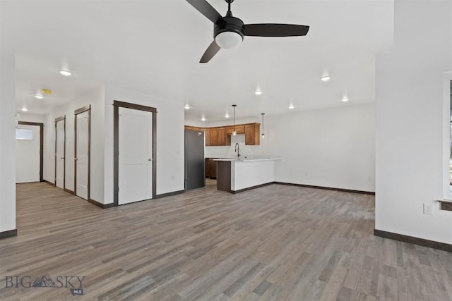 unfurnished living room featuring ceiling fan and light hardwood / wood-style flooring