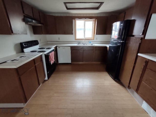 kitchen featuring black appliances, dark brown cabinetry, sink, and light hardwood / wood-style flooring