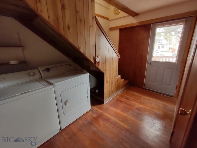 laundry room featuring washing machine and dryer, light hardwood / wood-style floors, and wooden walls