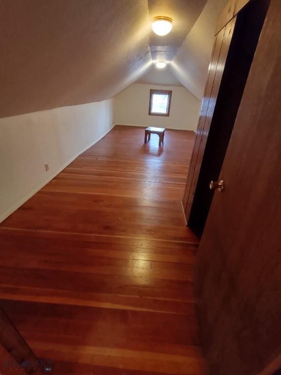 bonus room with vaulted ceiling and dark hardwood / wood-style floors