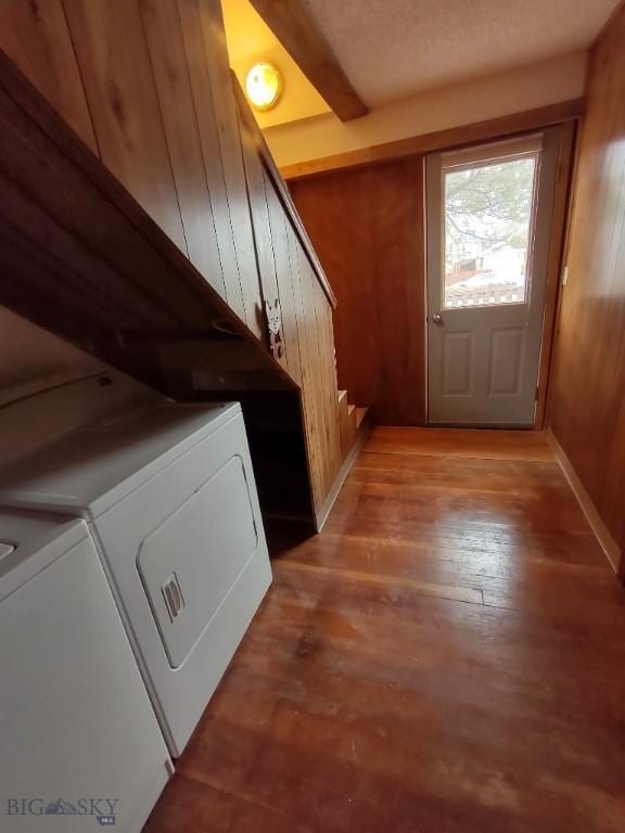 interior space with hardwood / wood-style flooring, wood walls, and independent washer and dryer