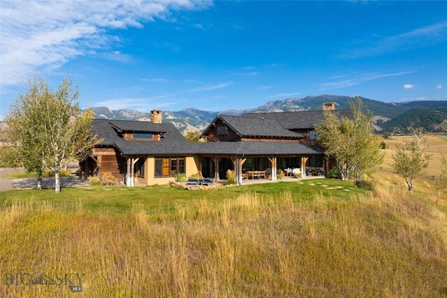 back of property with a mountain view and a patio