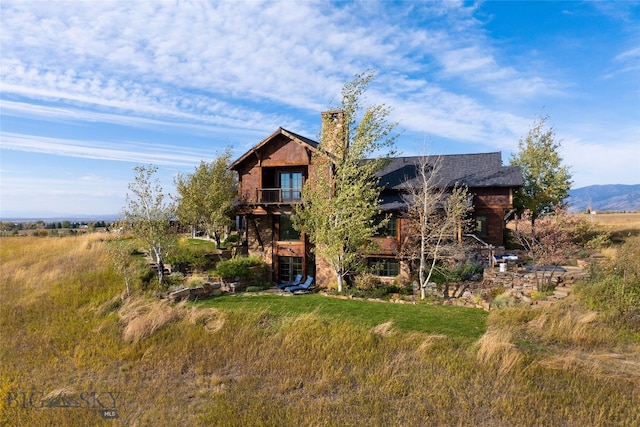 back of house featuring a mountain view and a balcony