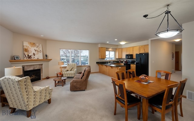 carpeted dining area with a tile fireplace