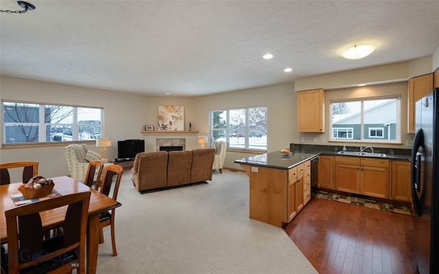 kitchen featuring sink, kitchen peninsula, a fireplace, black appliances, and hardwood / wood-style flooring