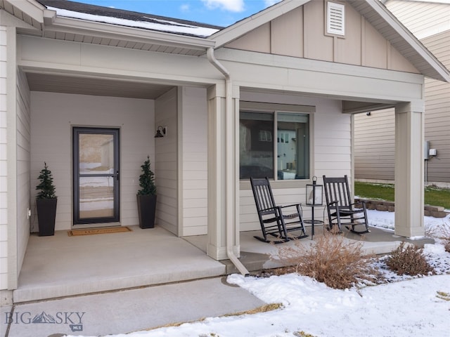 snow covered property entrance with covered porch