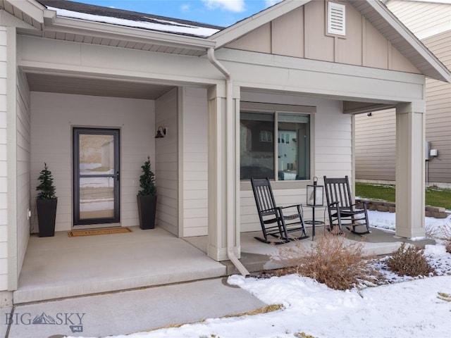 snow covered property entrance with covered porch