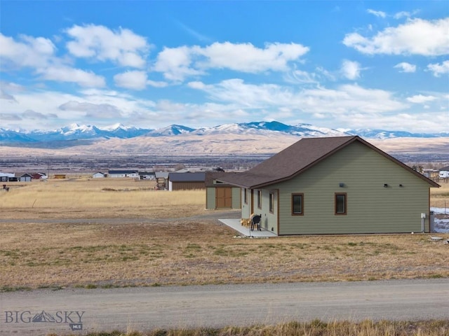 view of side of property with an outdoor structure, a shed, and a mountain view