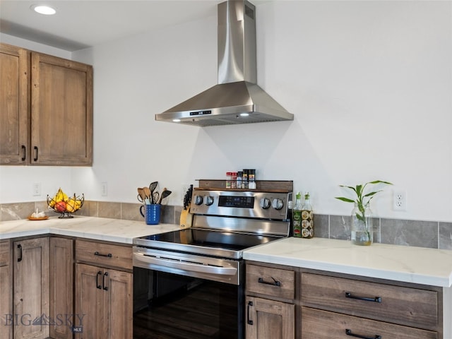 kitchen featuring stainless steel range with electric cooktop, light stone countertops, and wall chimney exhaust hood