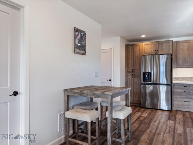 kitchen with stainless steel fridge, dark wood finished floors, baseboards, visible vents, and recessed lighting