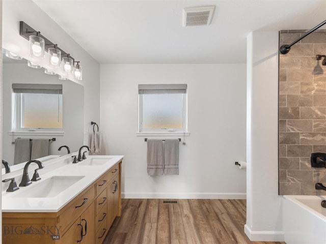 full bathroom with double vanity, wood finished floors, visible vents, and a sink