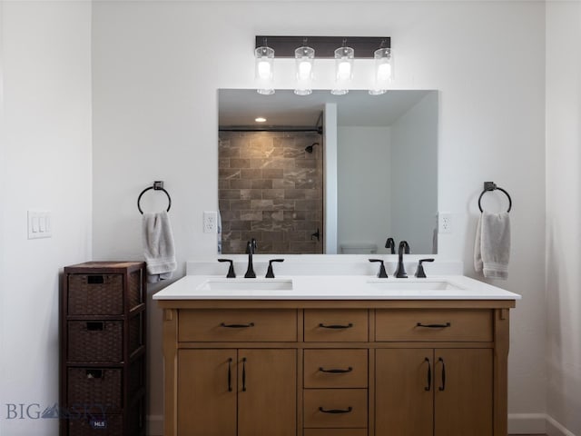 bathroom featuring a sink, double vanity, and tiled shower