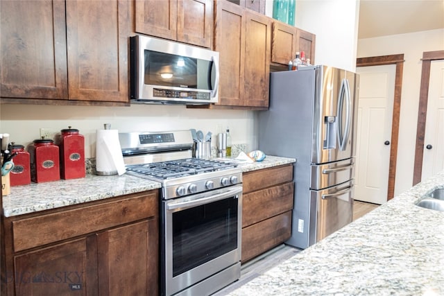 kitchen featuring light stone countertops, stainless steel appliances, and light hardwood / wood-style floors