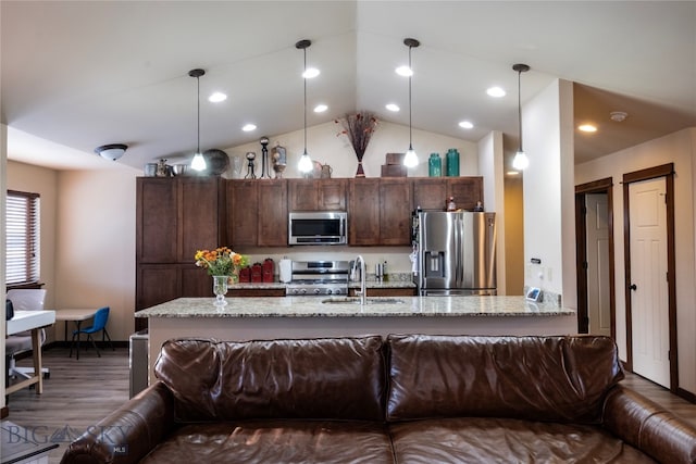 kitchen featuring light stone countertops, sink, stainless steel appliances, lofted ceiling, and decorative light fixtures