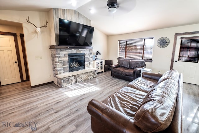 living room with ceiling fan, light hardwood / wood-style floors, lofted ceiling, and a fireplace