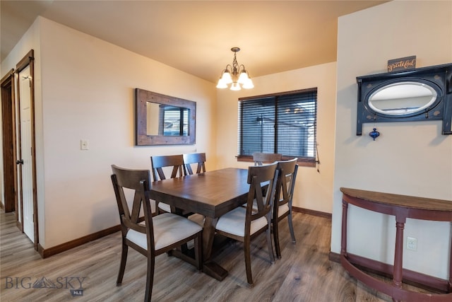 dining area with hardwood / wood-style flooring and a notable chandelier