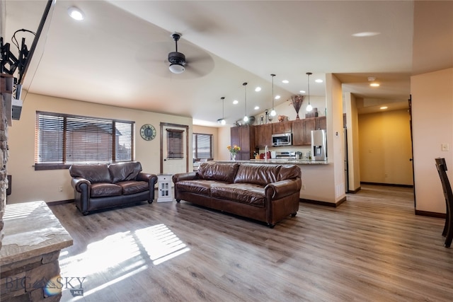 living room featuring ceiling fan, hardwood / wood-style floors, and vaulted ceiling