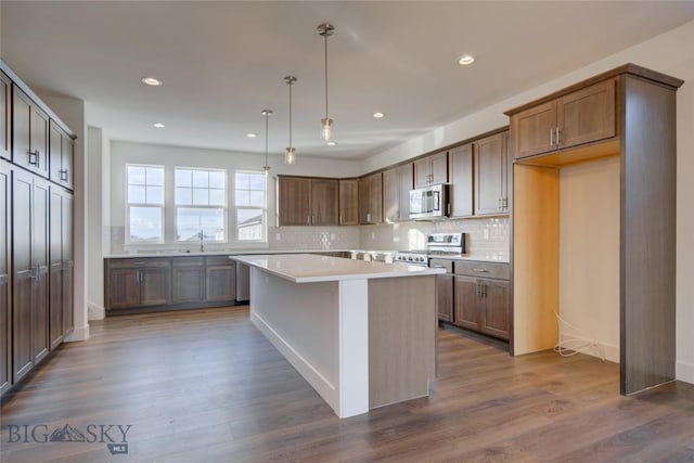 kitchen featuring decorative light fixtures, a center island, stainless steel appliances, and dark hardwood / wood-style floors