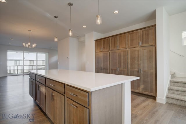 kitchen featuring light wood-type flooring, a center island, decorative light fixtures, and a notable chandelier