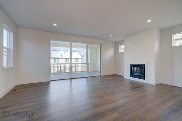 unfurnished living room with a wealth of natural light and dark hardwood / wood-style floors