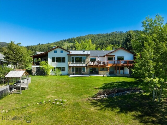 rear view of property featuring a lawn and a deck