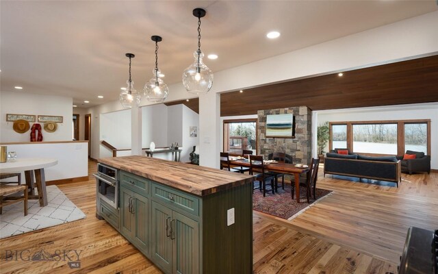 kitchen with wooden counters, oven, green cabinetry, light hardwood / wood-style floors, and a kitchen island