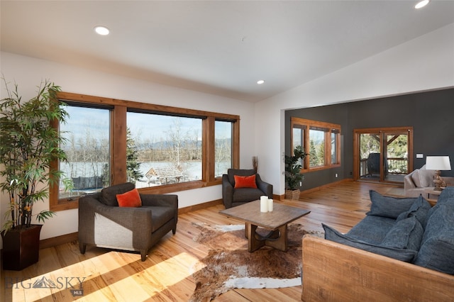 living room with light hardwood / wood-style floors, lofted ceiling, and a wealth of natural light