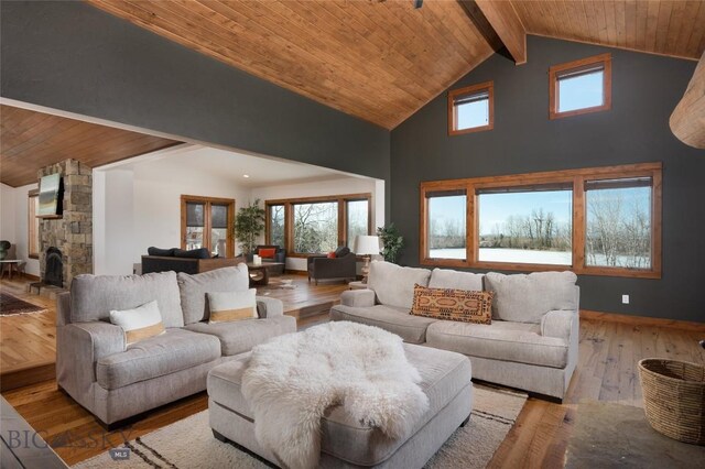 living room featuring lofted ceiling with beams, light wood-type flooring, a fireplace, and wooden ceiling