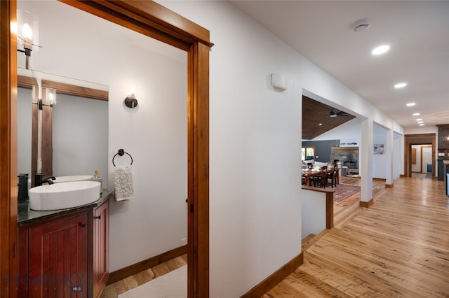 hallway featuring lofted ceiling, sink, and light hardwood / wood-style flooring