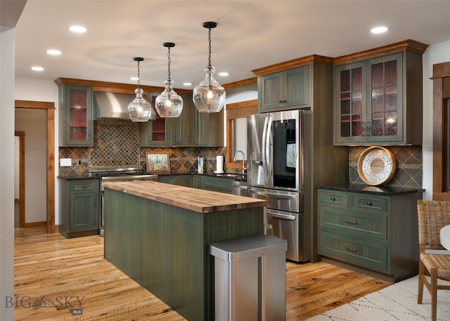 kitchen with wood counters, light wood-type flooring, wall chimney range hood, and decorative light fixtures