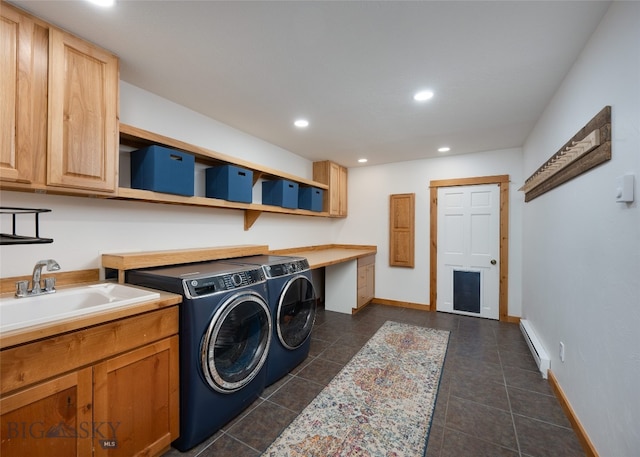 clothes washing area featuring washing machine and clothes dryer, sink, cabinets, a baseboard heating unit, and dark tile patterned flooring