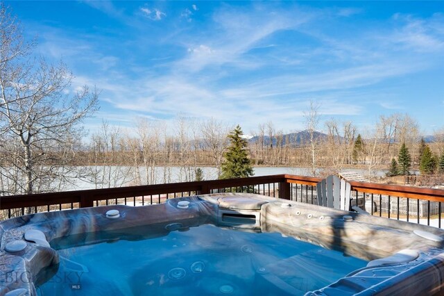 snow covered deck with a mountain view and a hot tub