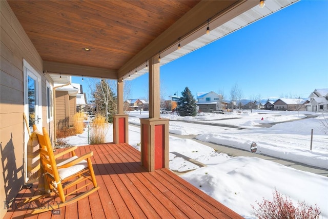 snow covered deck featuring a porch and a residential view