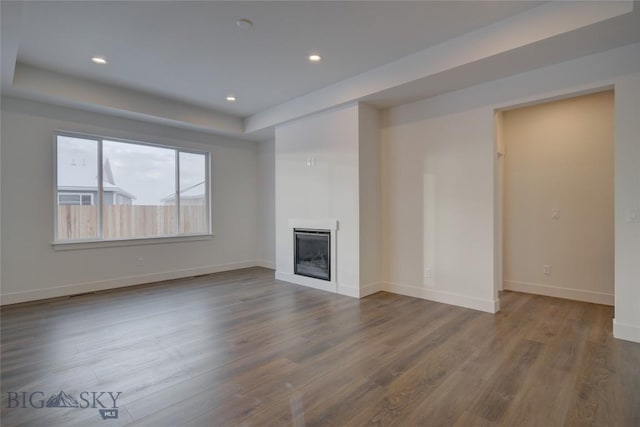 unfurnished living room with hardwood / wood-style flooring and a tray ceiling