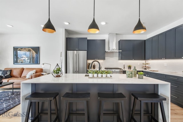 kitchen featuring pendant lighting, wall chimney exhaust hood, light hardwood / wood-style floors, and appliances with stainless steel finishes