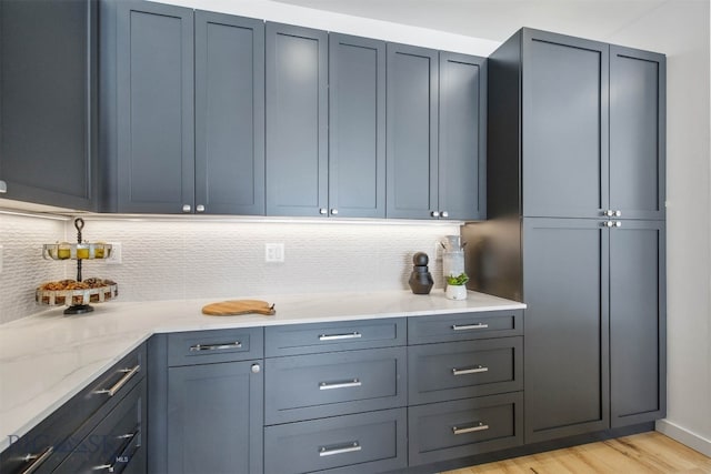 kitchen featuring decorative backsplash, light hardwood / wood-style floors, and light stone countertops