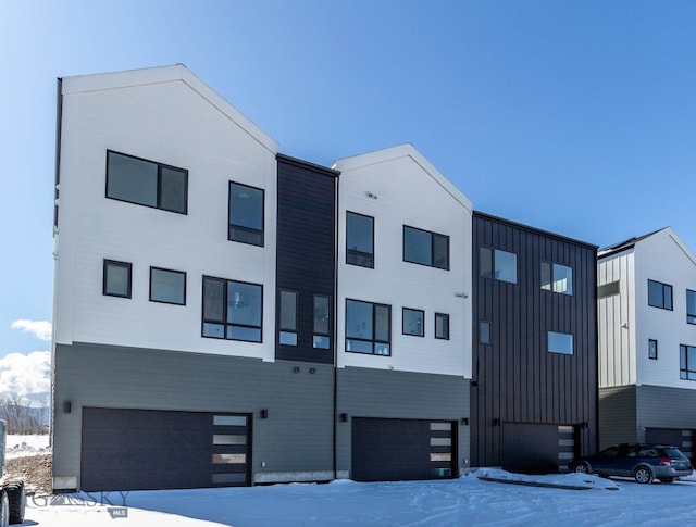 snow covered property with a garage