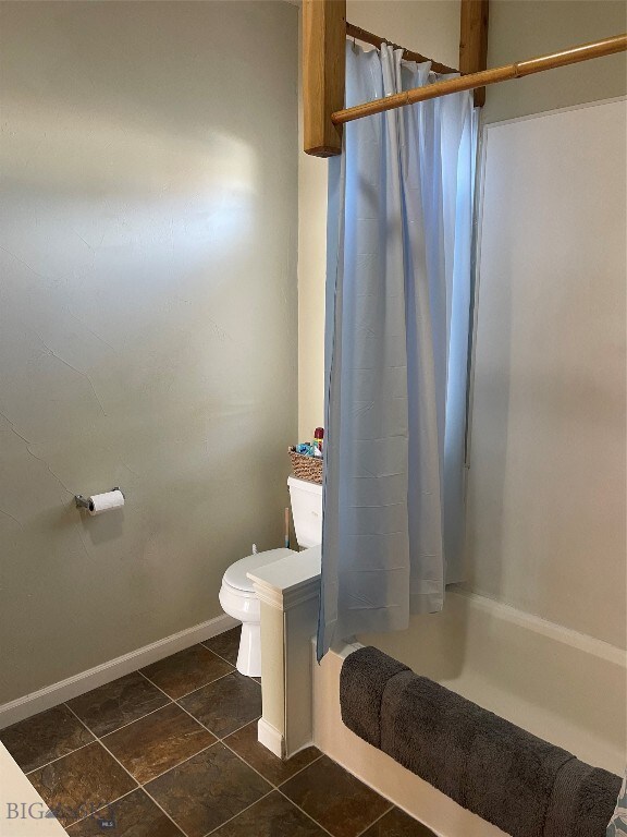 bathroom with shower / tub combo, toilet, and tile patterned floors