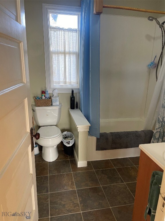 full bathroom featuring tile patterned flooring, vanity, toilet, and shower / bath combo with shower curtain