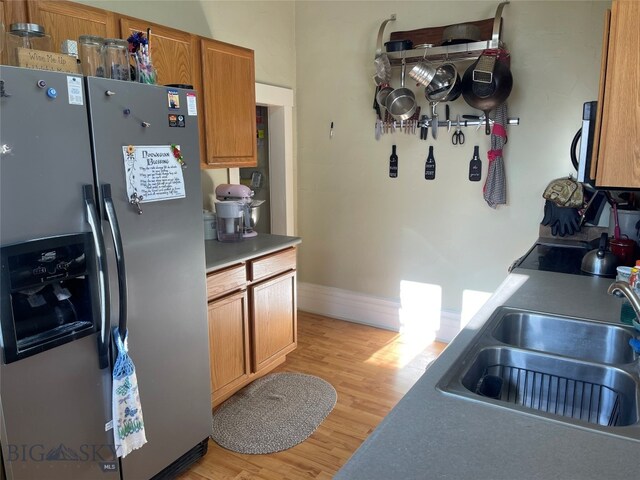 kitchen with stainless steel refrigerator with ice dispenser, light wood-type flooring, and sink