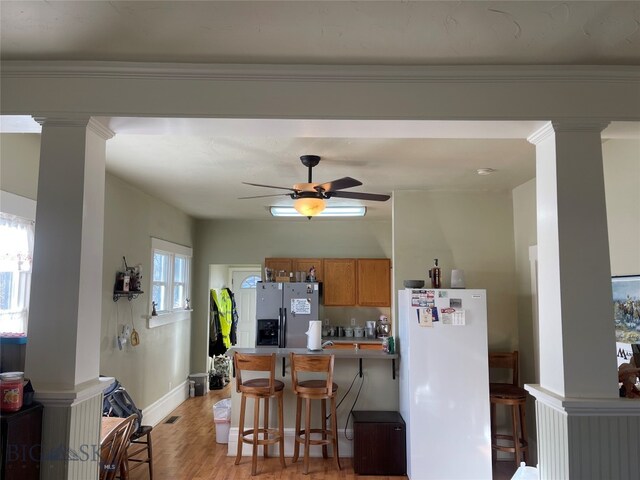 kitchen with a kitchen bar, stainless steel refrigerator with ice dispenser, white fridge, and plenty of natural light