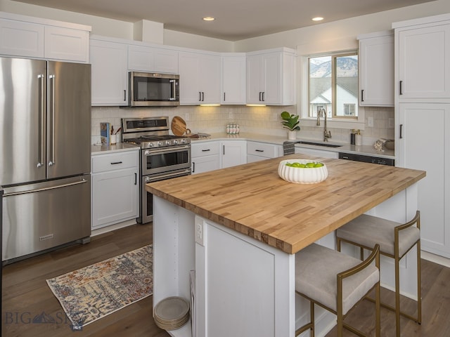 kitchen with white cabinets, premium appliances, a kitchen island, and sink