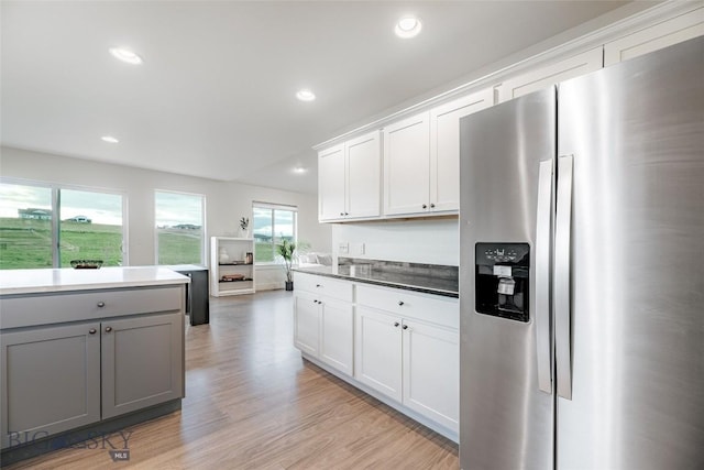 kitchen with stainless steel fridge, gray cabinets, light hardwood / wood-style floors, and white cabinetry