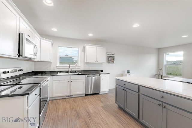 kitchen featuring appliances with stainless steel finishes, light wood-type flooring, sink, gray cabinets, and white cabinetry