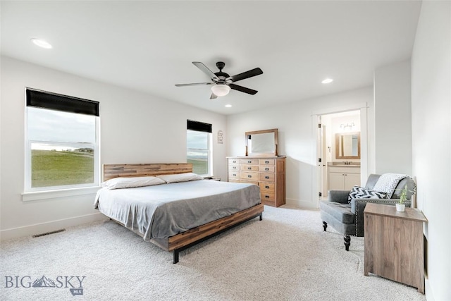 carpeted bedroom featuring connected bathroom, multiple windows, and ceiling fan