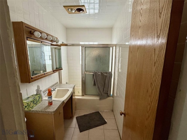 bathroom featuring backsplash, bath / shower combo with glass door, vanity, tile walls, and tile patterned flooring