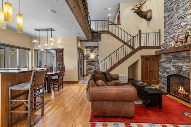 living room with a stone fireplace and light wood-type flooring