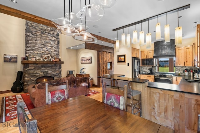 dining room featuring sink, a fireplace, beamed ceiling, and light wood-type flooring