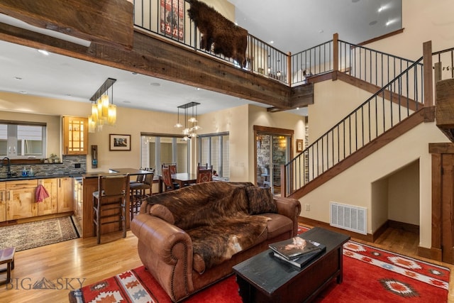 living room with beamed ceiling, light hardwood / wood-style floors, a healthy amount of sunlight, and sink