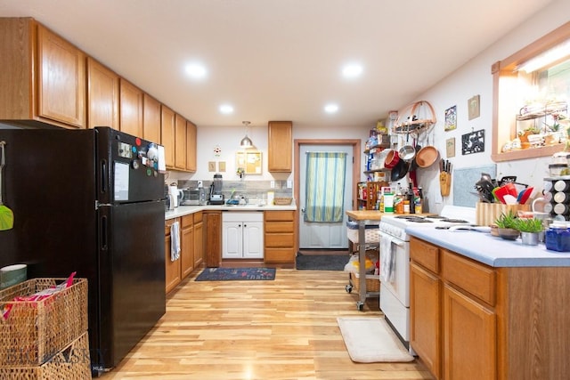 kitchen featuring white range with electric stovetop, black fridge, light hardwood / wood-style flooring, and pendant lighting